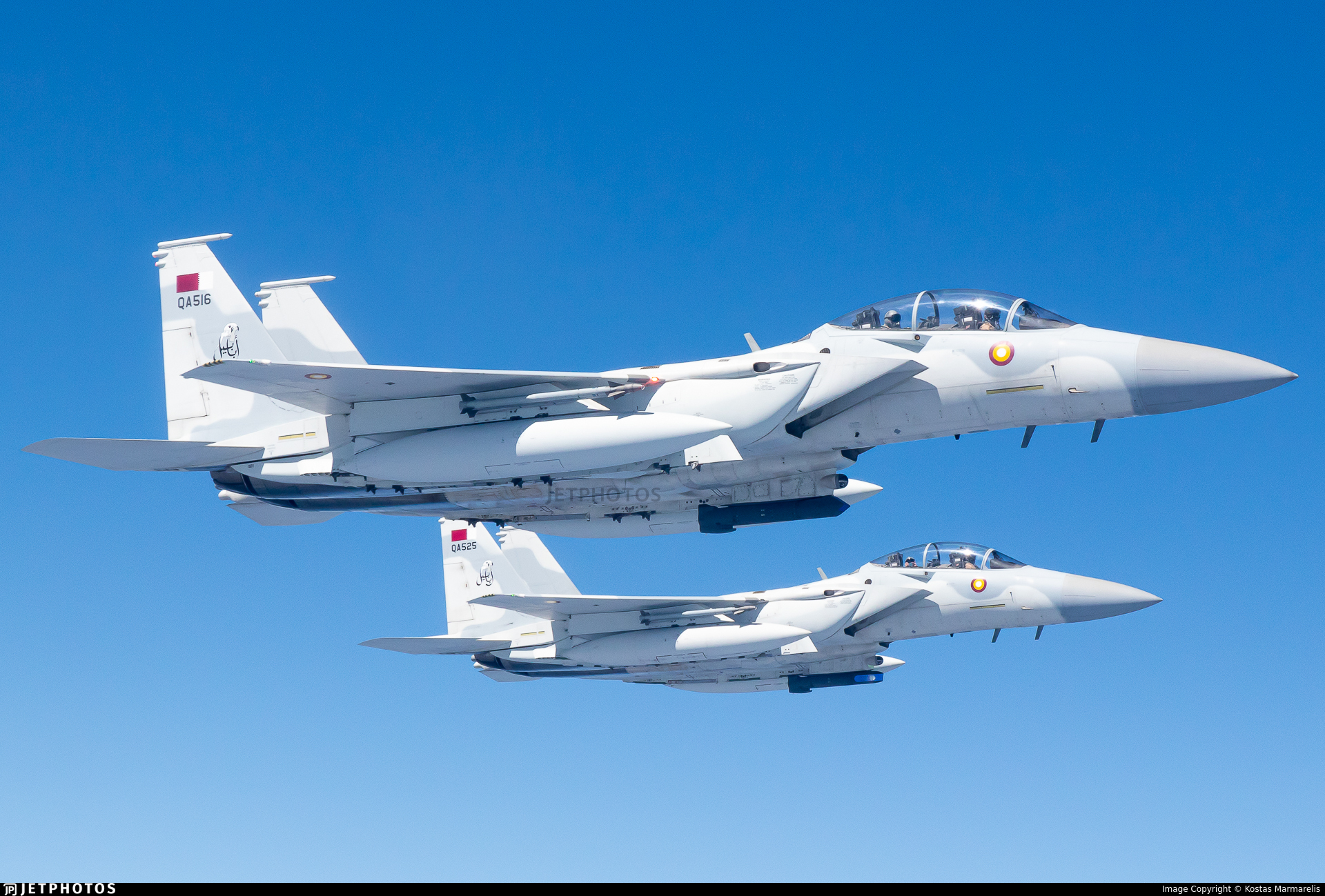 Two F‑15 fighter jets flying in close formation against a clear blue sky