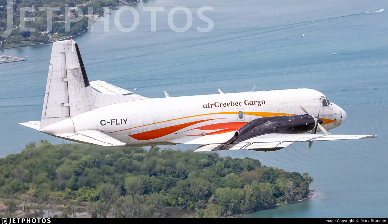 Air Creebec cargo turboprop aircraft flying over a lake and peninsula
